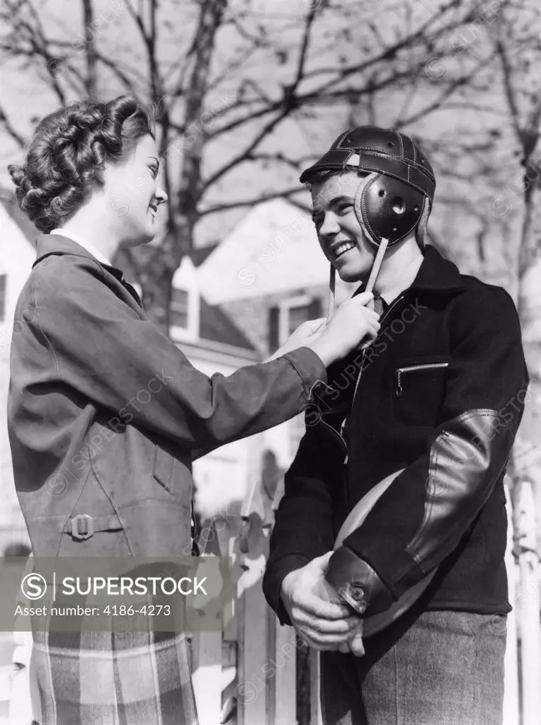 1940S Cute Romantic Teen Couple Girl Holding Straps Of Boys Football Helmet