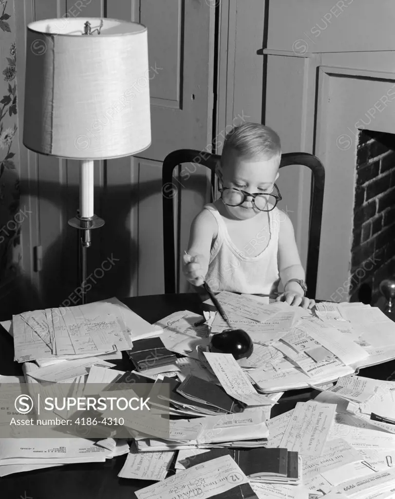 1960S Young Boy At Desk Wearing Glasses And Undershirt Examining Personal Financial Documents Receipts Tax Forms Irs Audit