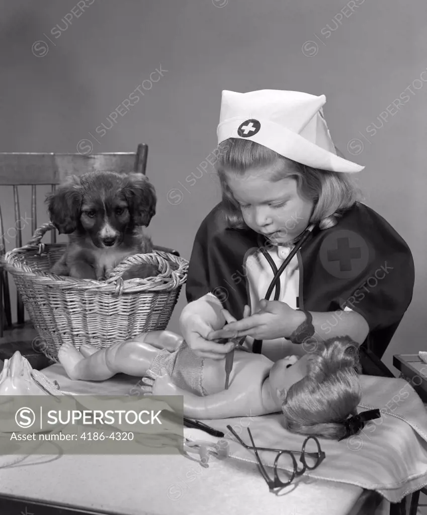 1950S Girl Wearing Nurse'S Uniform Putting Bandages On A Doll While A Puppy Dog In A Basket Behind Her Watches