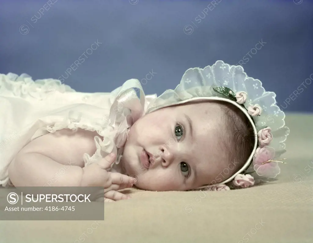 1950S Baby Girl Lying On Beige Blanket Wearing Baby Bonnet With Lace And Pink Rosebud Trim Spring Season
