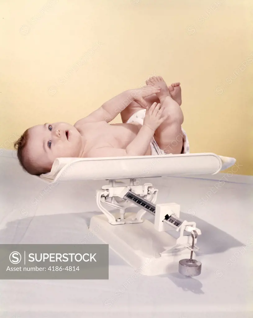 1950S 1960S Smiling Baby Lying On Weight Scale