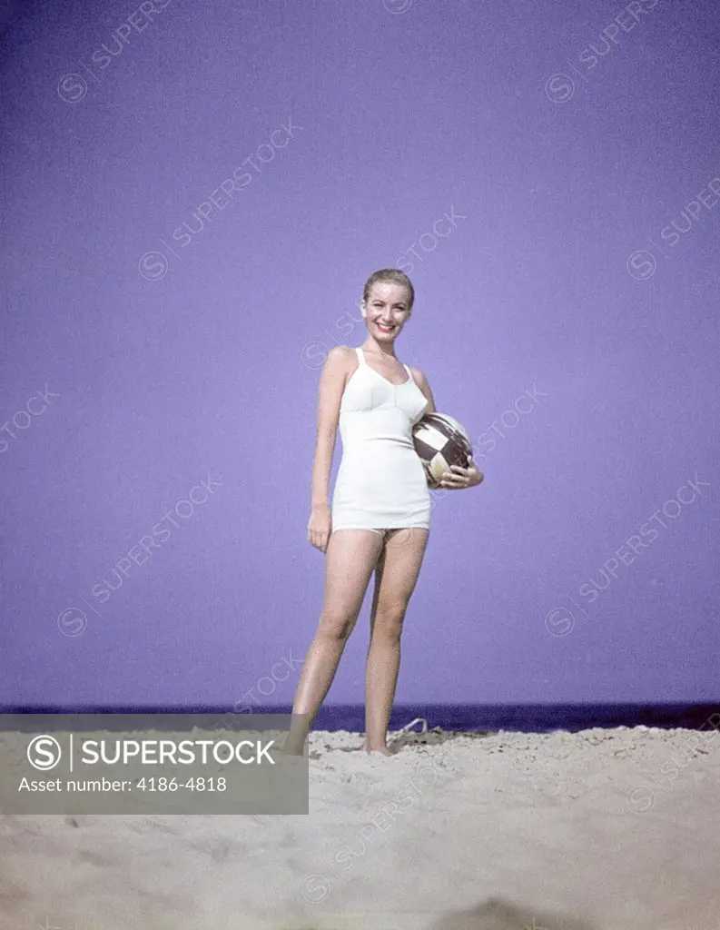 1950S Full Length Portrait Woman Light Blue One Piece Bathing Suit Swim Wear Standing On Sand Holding Beach Ball Fashion