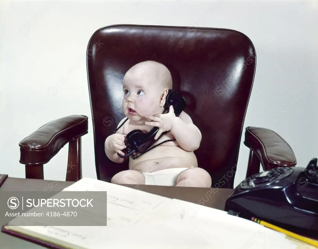 1960S Chubby Baby Sitting In Leather Chair At Office Desk Holding Telephone