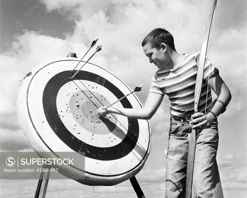 1960S Boy Jeans Striped T-Shirt Holding Bow & Pulling Arrow Out Of Target Bull'S-Eye  