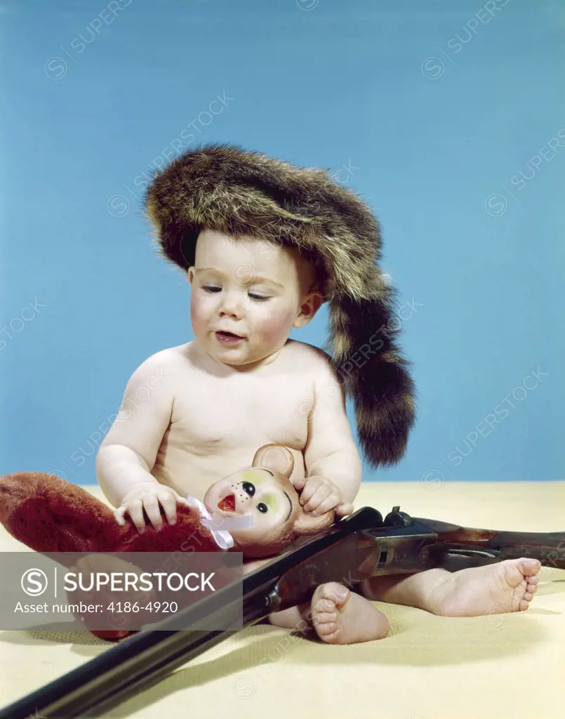 1960S Baby Boy Wearing Coonskin Cap With Stuffed Animal And Shotgun