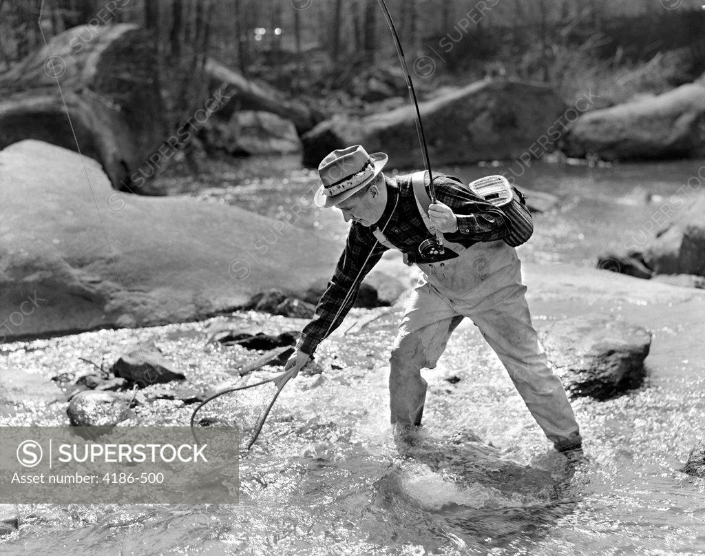 1930S 1940S Man Fly Fishing Wearing Waders Holding Rod And Netting A  Successful Catch - SuperStock
