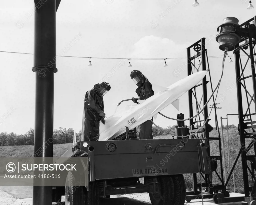 1960S U.S. Army Nike Guided Missile On Launch Pad Being Fueled Fuel By 2 Men In Fire Resistant Clothing
