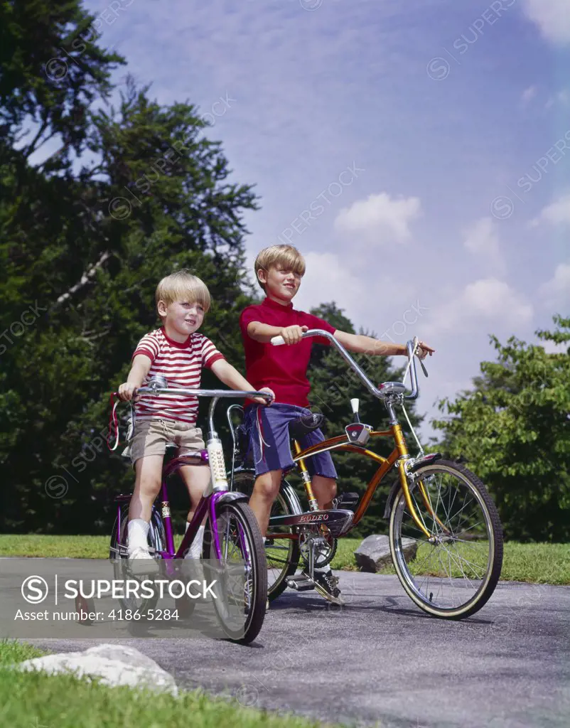 1970S 1960S Two Boys Riding Bikes In Park Summer