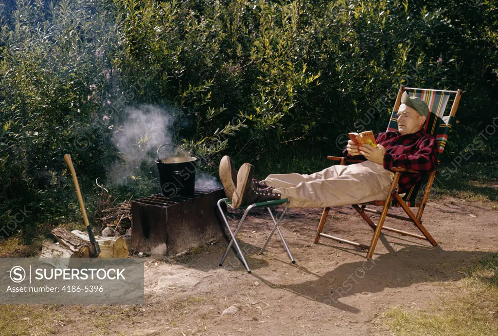 1950S Man Reading Sitting Folding Camp Chair Campfire Grill Pot Smoke Axe Fire Wood Pattison State Park Wisconsin
