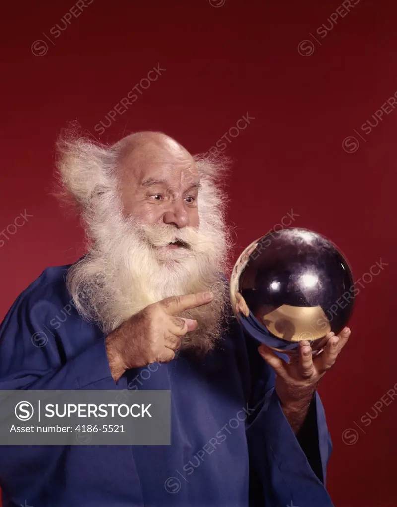 Balding White Haired Man In Robe Looking At Silver Ball He Is Holding Studio