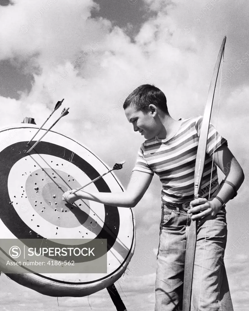 1950S Boy Jeans Striped T-Shirt Holding Bow & Pulling Arrow Out Of Target Bull'S-Eye  