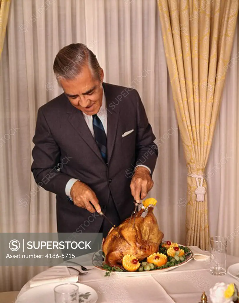 1960S Senior Man Carving Turkey At Dining Room Table Holiday Meal Christmas Thanksgiving