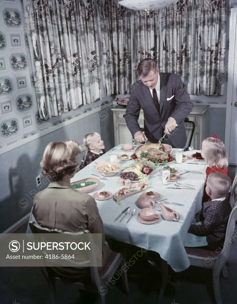 1950S Family 5 Sitting At Dining Room Table Dad Carves Turkey At Head Of Table