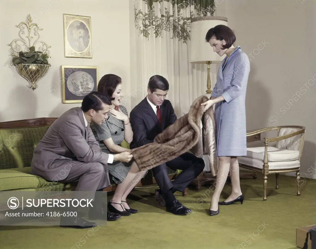Woman Showing Fur Coat To Two Men And A Woman In Living Room Indoor Lifestyle Gift