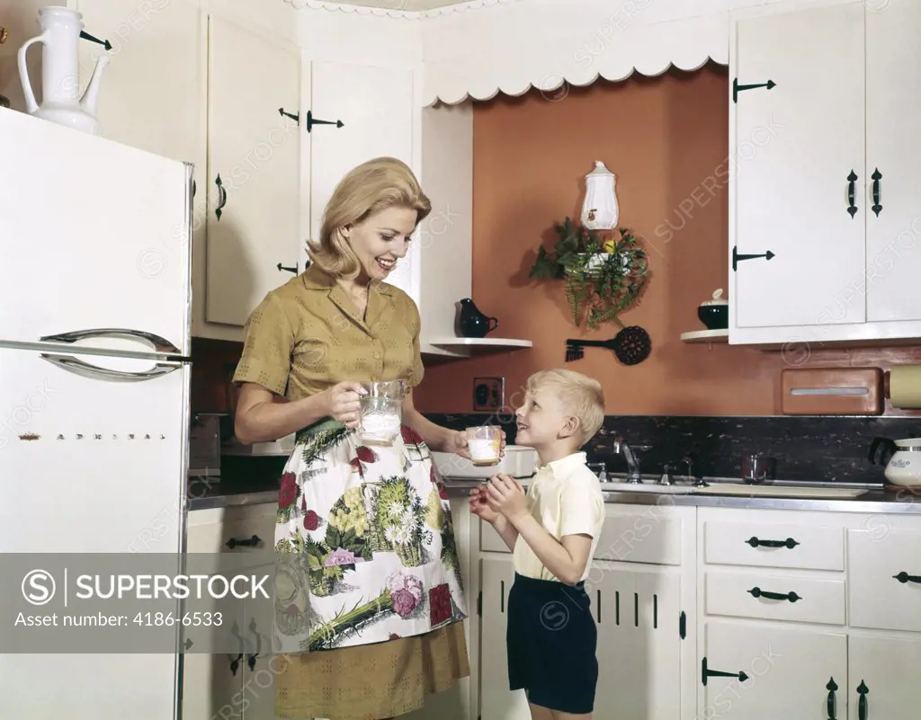 1970S Mother Handing Glass Of Milk To Son In Kitchen
