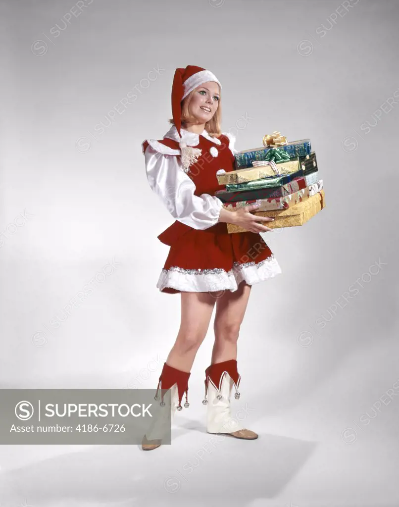1960S Young Woman In Christmas Santa Helper Red And White Costume And Cap Holding Pile Of Gift Wrapped Presents