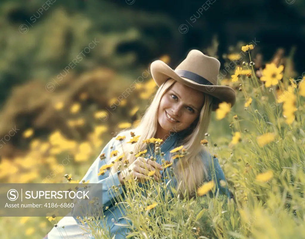 1970S Retro Blond Woman Wearing Cowboy Hat Sitting In A Field Of Buttercup Wild Flowers Smiling