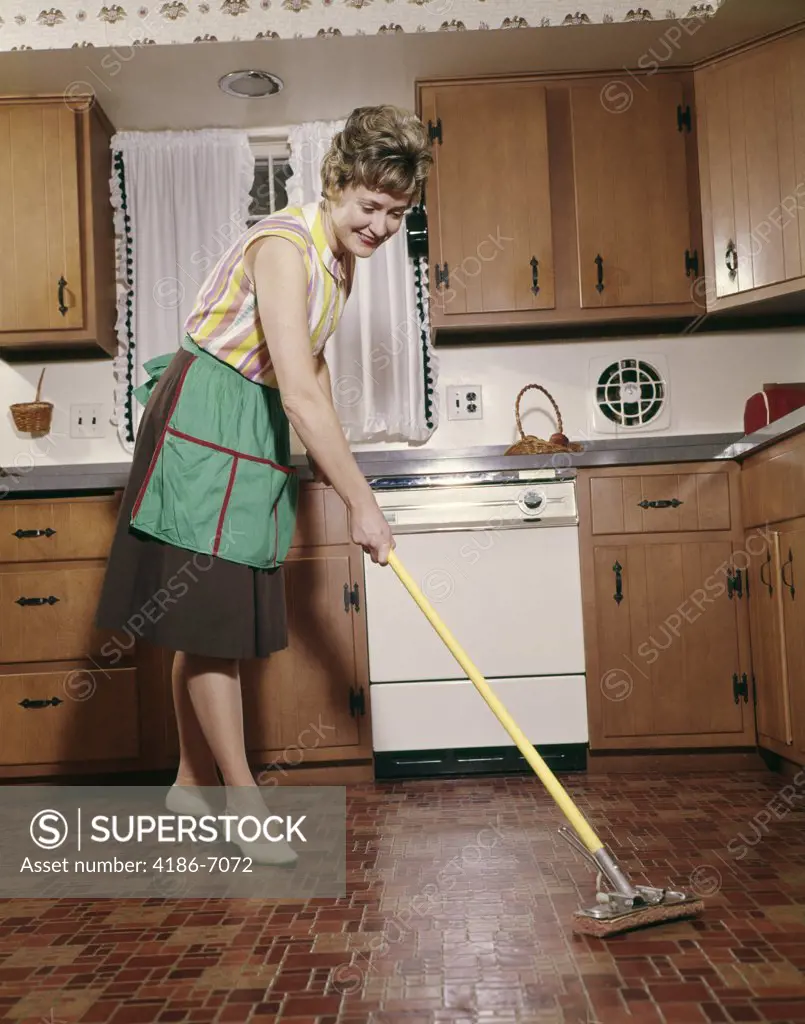 1960S Woman In Apron Cleaning Kitchen Floor With Sponge Mop