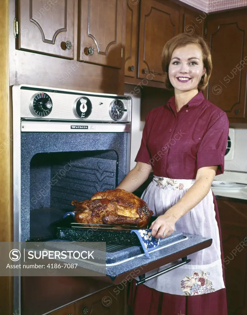 1960S Smiling Woman Taking Turkey Out Of Oven Indoor Food Poultry