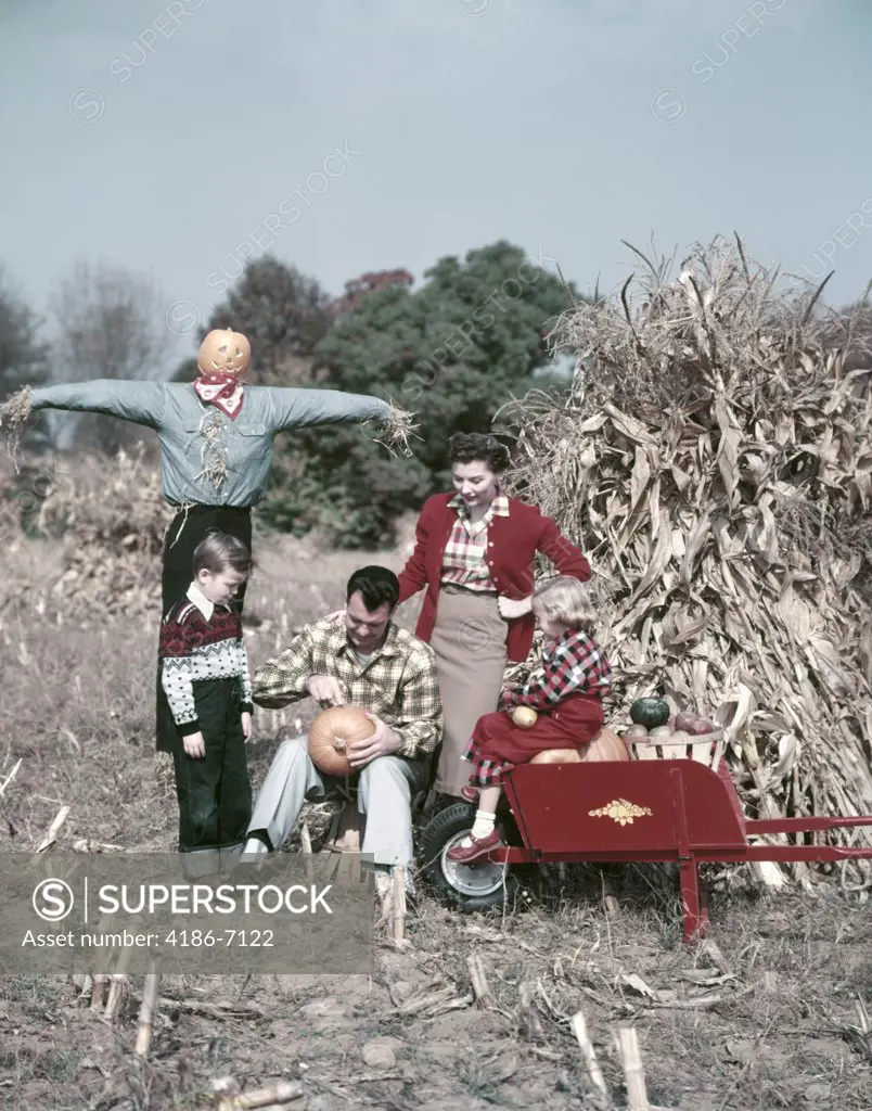 1950S Family Man Father Woman Mother Boy Son Girl Daughter In Autumn Corn Field Carving Pumpkin Shocks Scarecrow Red Wheel Barrow