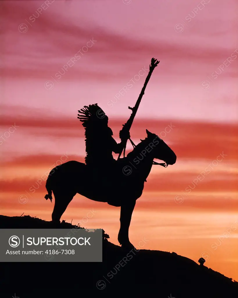 1930S Sunset Silhouette Of Native American Man Wearing Headdress On Horse At Top Of A Hill