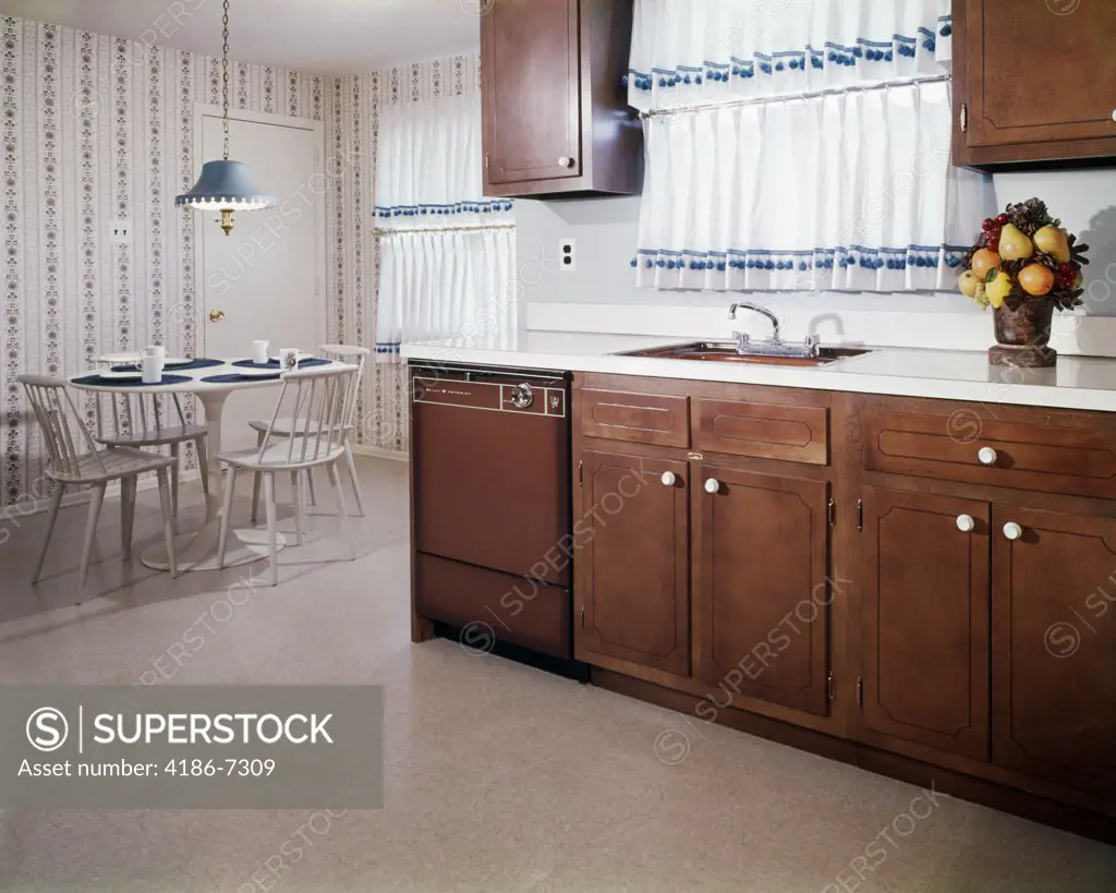 1970S Kitchen And Dining Area With Dark Wood Cabinets And Blue And White Curtains