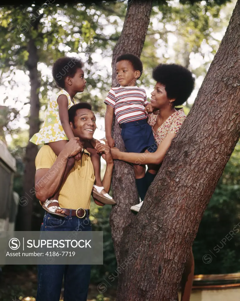 1970S African-American Family Mother Father Two Children  Outdoor  By Tree Trunk