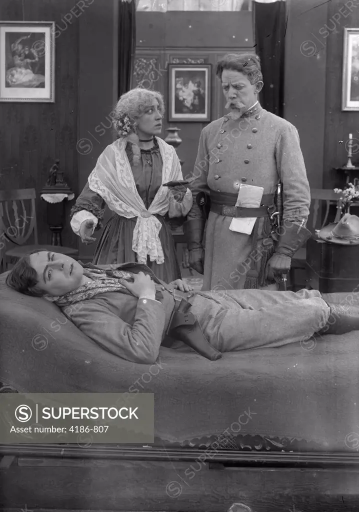 Woman And Civil War Confederate Soldier Watching Over Sick Man Lying On Bed Silent Movie Still