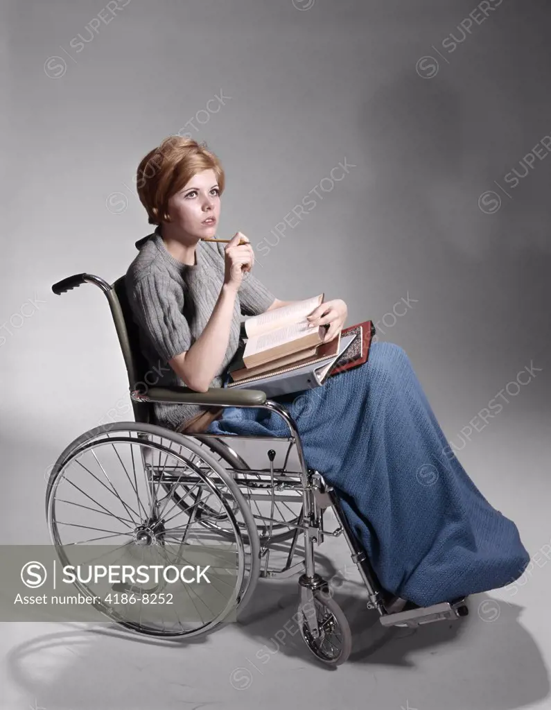 1960S Serious Young Woman Student Sitting In Wheelchair Pile Of Books On Lap
