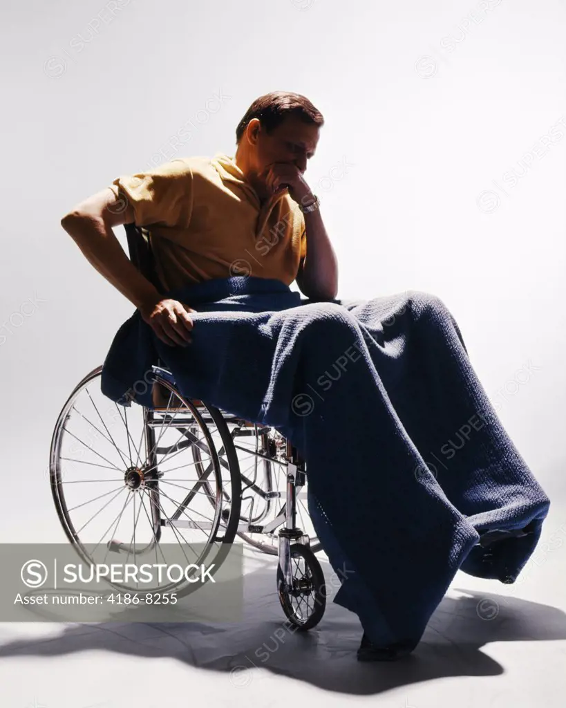 1960S Sad Man Sitting In Wheelchair Blanket Wrapped Around Legs Leaning Chin On Hand