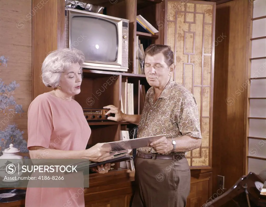 1960S Mature Couple Man And Woman Playing 33 Rpm Phonograph Records At Home Entertainment Center