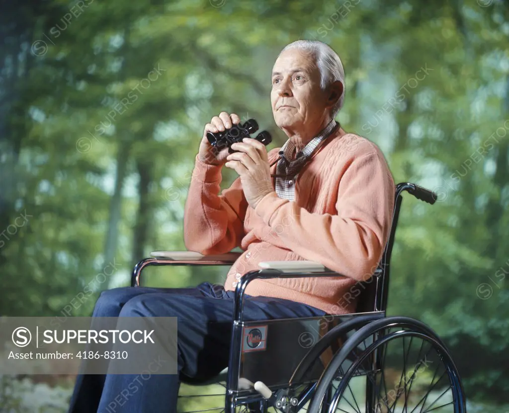 1970S Senior Man Sitting In Wheelchair Outdoors Using Binoculars Bird Watching