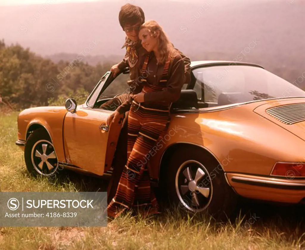 1970S Stylishly Dressed Couple Standing Together Leaning On A Convertible Porsche Automobile Sports Car