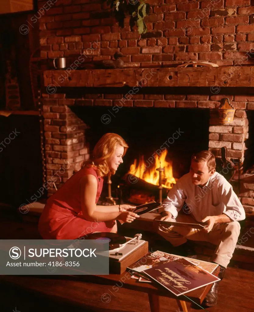 1960S 1970S Couple Man Woman By Living Room Fireplace Playing Vinyl Record Album Music On High Fidelity Stereo Turntable
