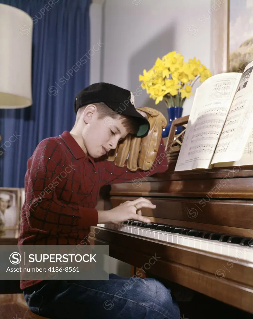1960S 1970S Impatient Annoyed Looking Boy With Baseball Cap And Glove Practicing Piano Lesson