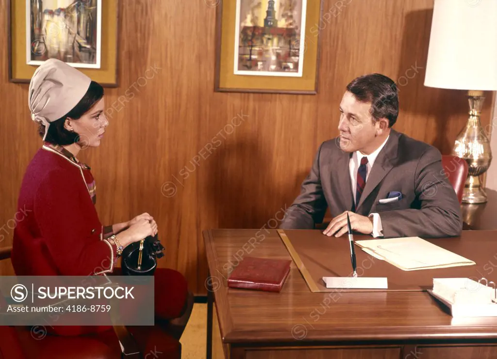 1960S Man Interviewing Woman At Desk In Office Indoor Business Meeting