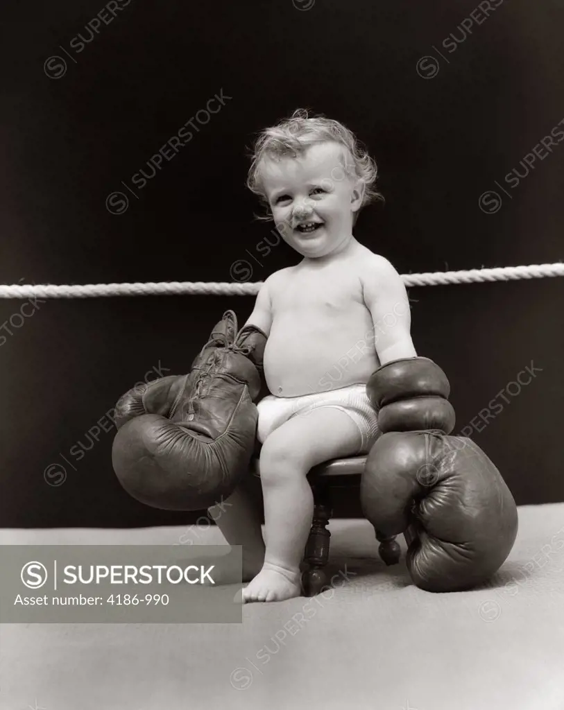 1930S Smiling Baby Seated On Stool In Boxing Ring Wearing Oversized Boxing Gloves Wearing Diaper