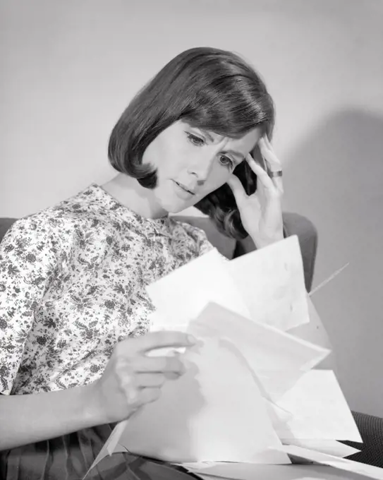 1960s WORRIED BRUNETTE WOMAN HOLDING A BUNCH OF BILLS AND PAPER WORK