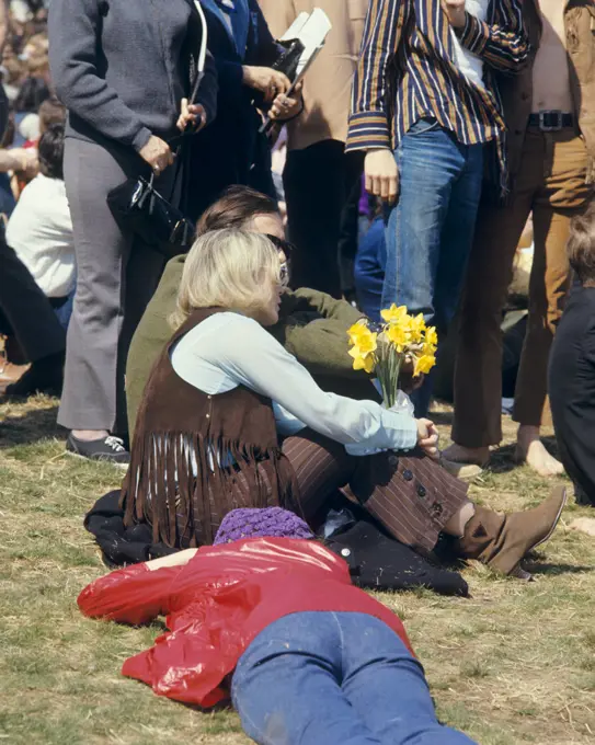 1960s BLONDE WOMAN IN FRINGED VEST HOLDING YELLOW DAFFODILS AMIDST CROWD 1969 PEACE RALLY FAIRMONT PARK PHILADELPHIA PA USA