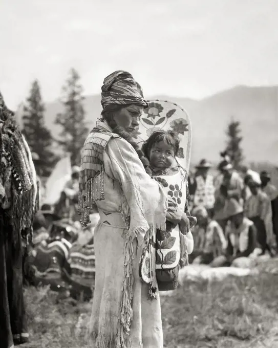 1920s 1930s NATIVE AMERICAN STONEY SIOUX INDIAN WOMAN MOTHER IN BEADED BUCKSKIN DRESS HOLDING BABY BOY GIRL IN PAPOOSE CANADA