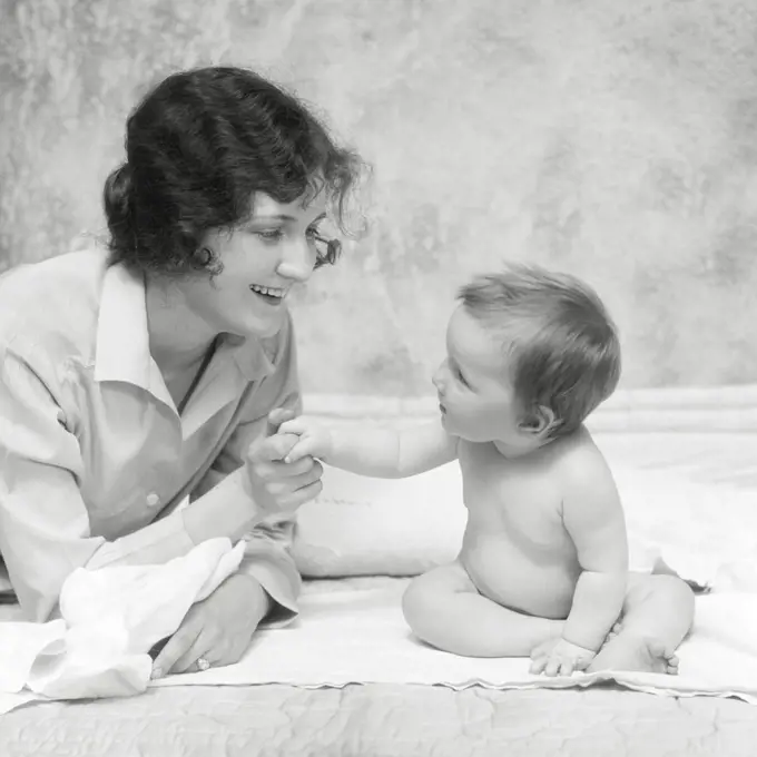 1920s SMILING BRUNETTE WOMAN MOTHER HOLDING HANDS FINGERS WITH BABY GIRL