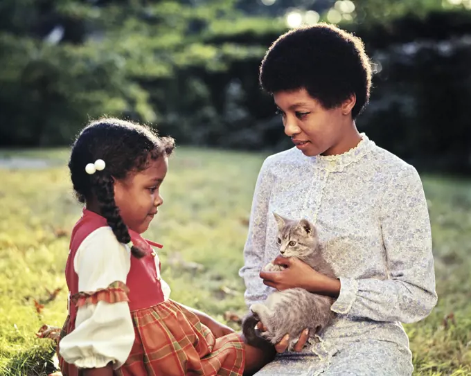 1970s 1960s MOTHER AND DAUGHTER IN BACKYARD MOTHER HOLDING A TABBY KITTEN