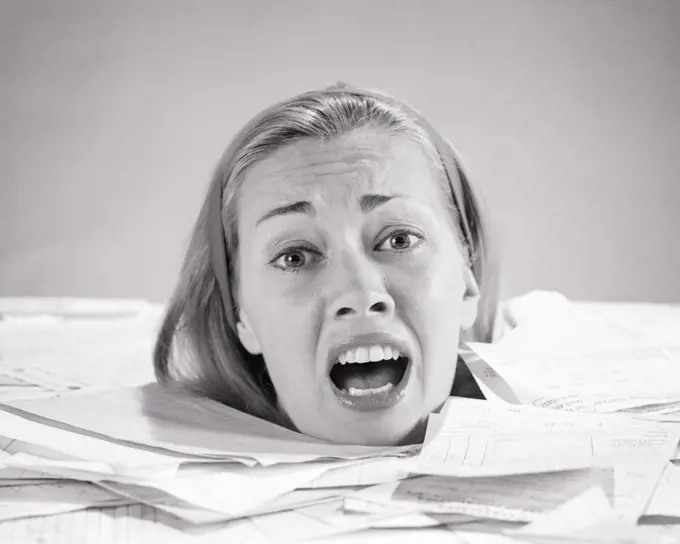 1960s WOMAN UP TO  HER NECK DROWNING IN PAPER BILLS INVOICES SHOUTING FOR HELP LOOKING AT CAMERA