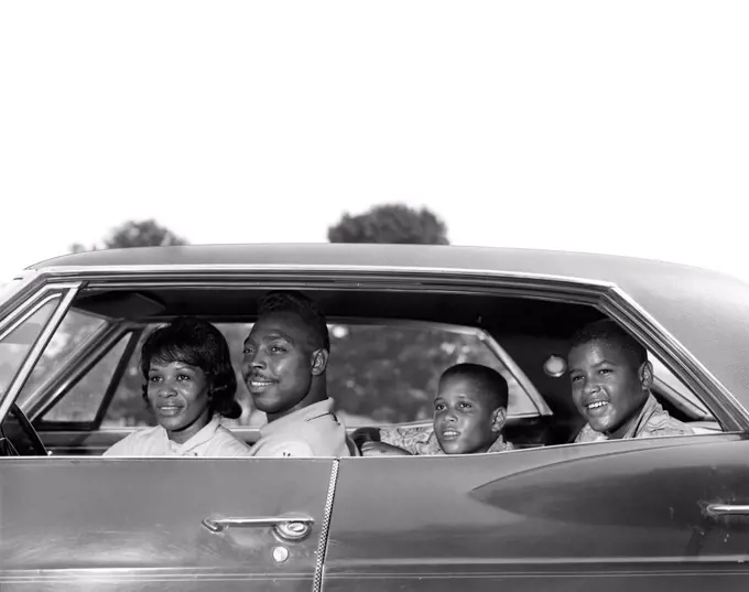 1960S Side View Outdoor Smiling African-American Family Father Mother Two Sons Sitting In Four Door Sedan Automobile