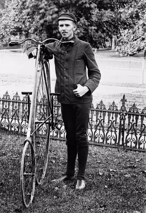 1880S 1890S Man Called Wheelman Wearing Clothing For Bicycle Riding Standing Next To High Wheel Ratchet Drive Bicycle