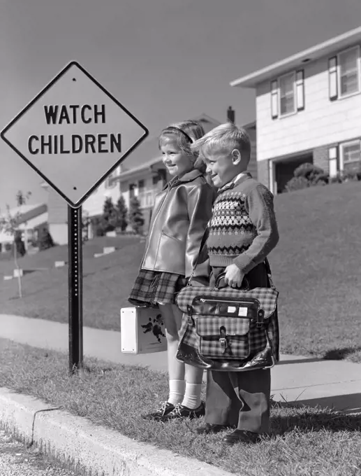 1950S Boy & Girl With Schoolbag & Lunch Pail On Suburban Curb With Sign Watch Children