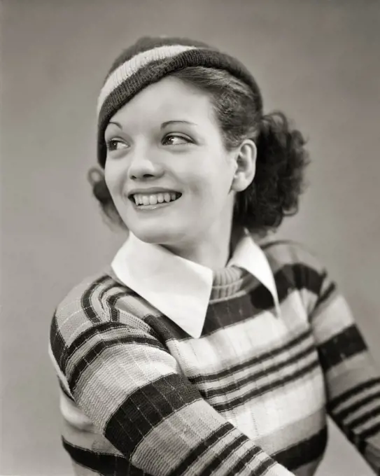 1930s SMILING BRUNETTE WOMAN LOOKING BACK OVER HER SHOULDER WEARING STRIPED KNIT SWEATER WHITE COLLAR AND STRIPED KNIT CAP