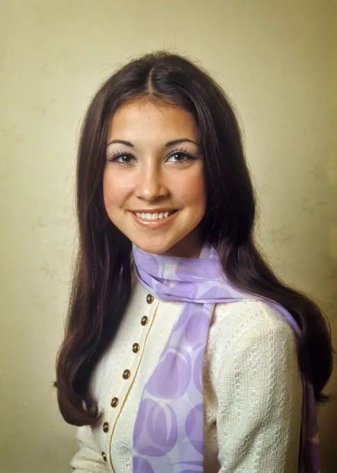 1970s PORTRAIT OF SMILING TEENAGE GIRL LOOKING AT CAMERA WITH LONG DARK HAIR AND EYES WEARING LAVENDER SCARF AT HER NECK