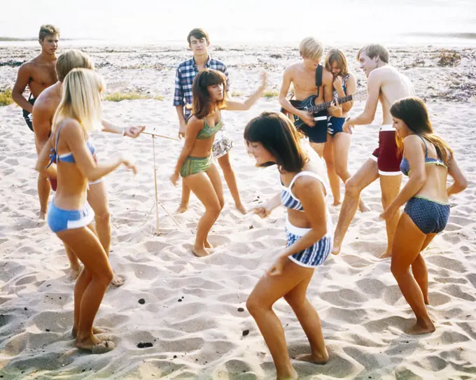 1960s 1970s ANONYMOUS BAND TEENAGE MUSICIANS AND COUPLES BOYS AND GIRLS WEARING BATHING SUITS DANCING TOGETHER AT A BEACH PARTY