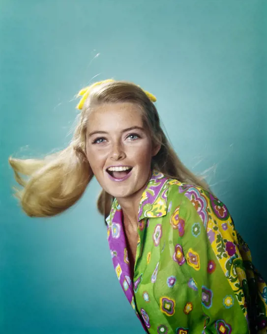1960s 1970s PORTRAIT SMILING HAPPY YOUNG WOMAN SWINGING BLONDE HAIR LOOKING AT CAMERA BRIGHT BLUE EYES WEARING PRINT SHIRT 